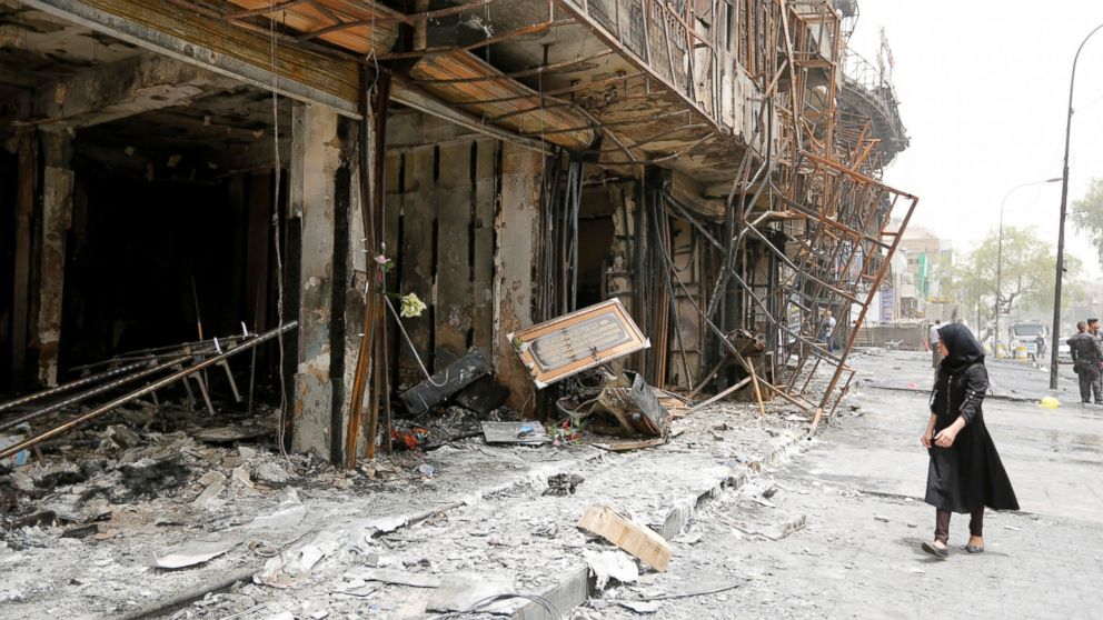 A girl walks past the site after a suicide car bomb attack at the shopping area of Karrada, a largely Shi'ite district, in Baghdad, Iraq on July 4, 2016.