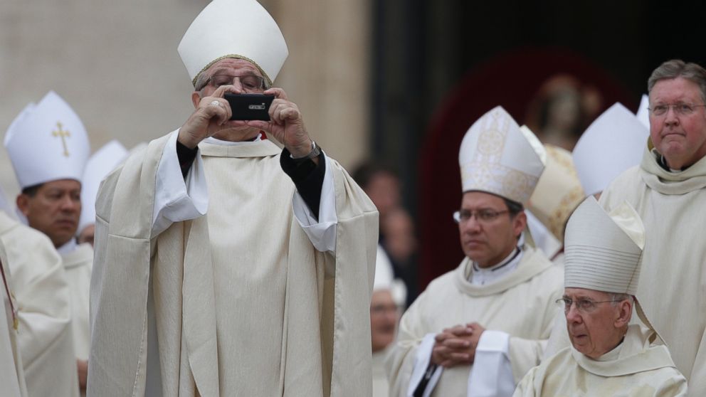 A bishop uses his mobile phone to take photographs as he arrives for the canonization ceremony of Popes John XXIII and John Paul II to start in St. Peter's Square at the Vatican April 27, 2014.     