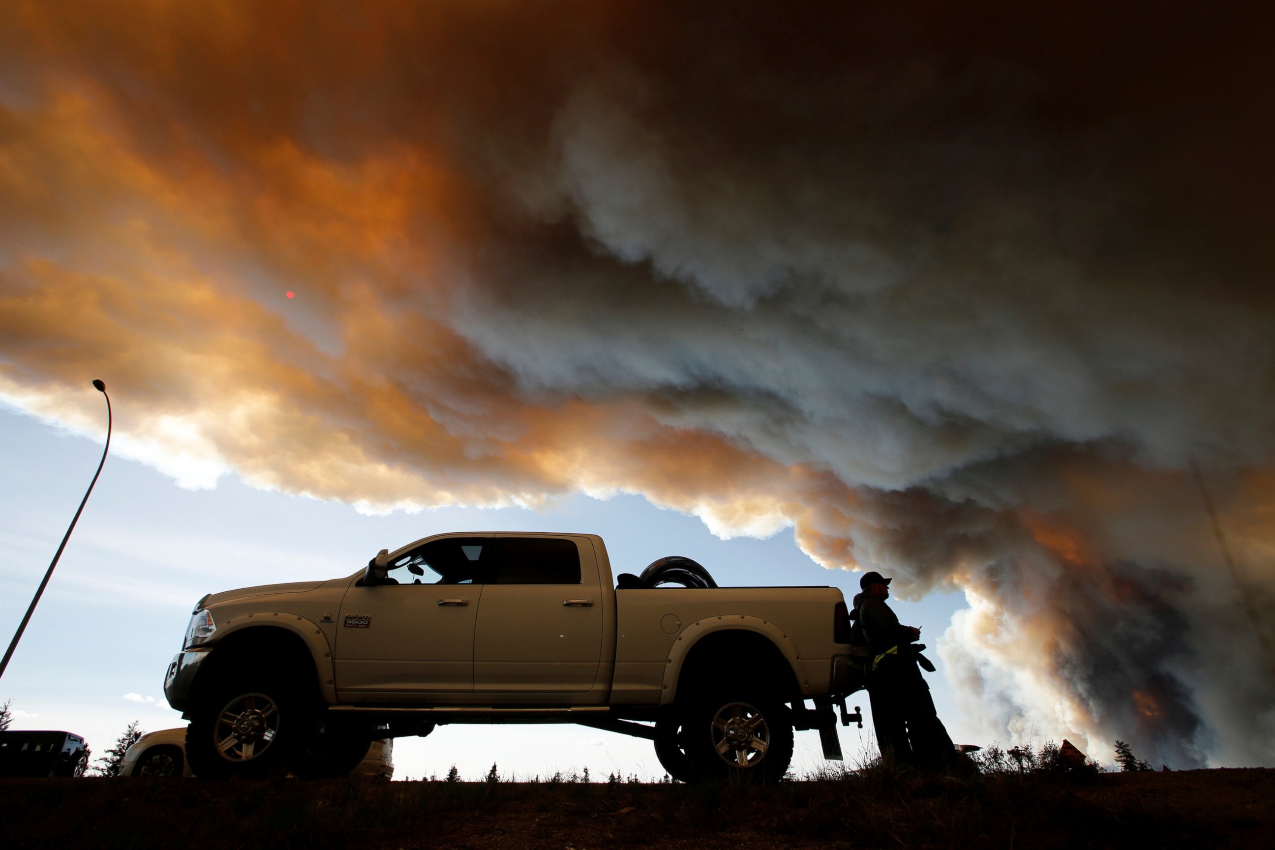 PHOTO: People wait at a roadblock as smoke rises from wildfires near Fort McMurray, Alberta, Canada, May 6, 2016. 