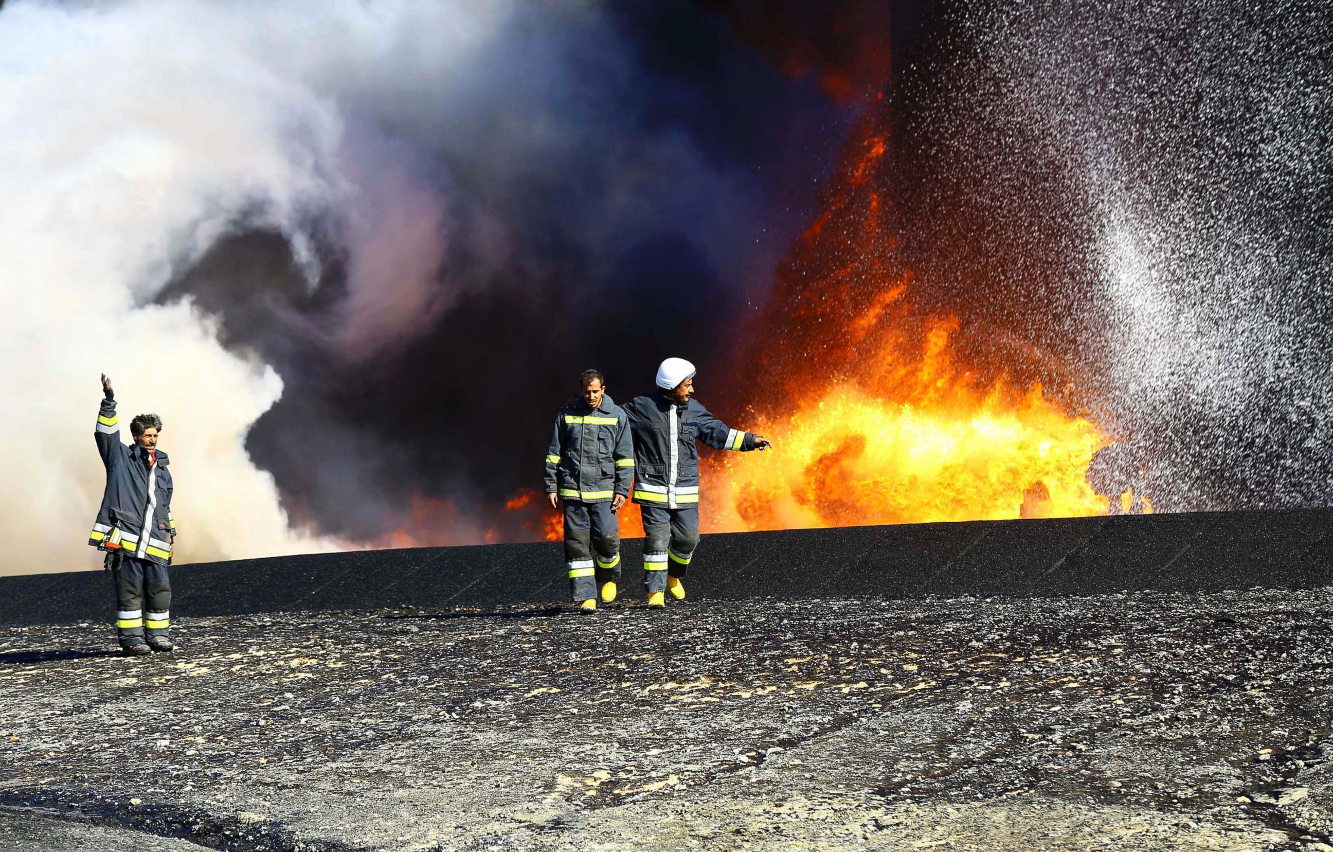 PHOTO: Firefighters walk near the fire of a storage oil tank at the port of Es Sider in Ras Lanuf, Libya in this Dec. 29, 2014 file photo.