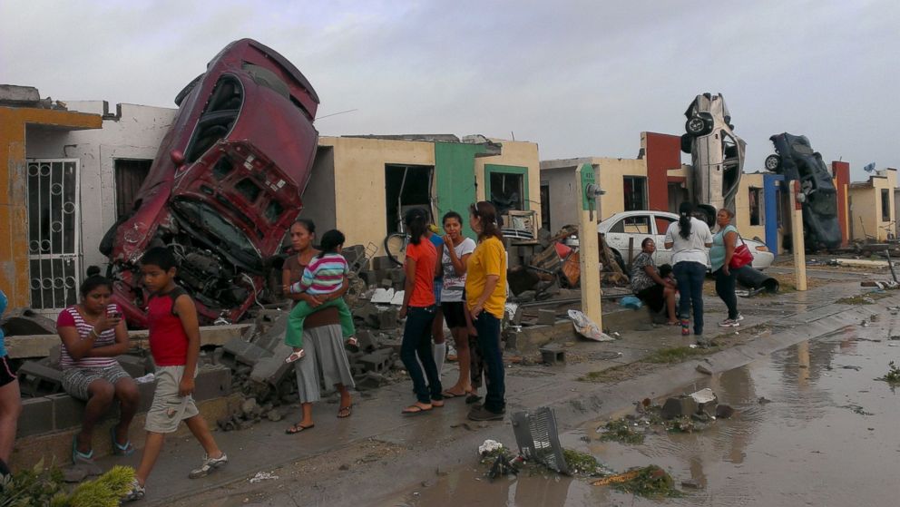 PHOTO: Residents stand outside their homes as damaged cars are seen after a tornado hit the town of Ciudad Acuna, state of Coahuila, May 25, 2015. 
