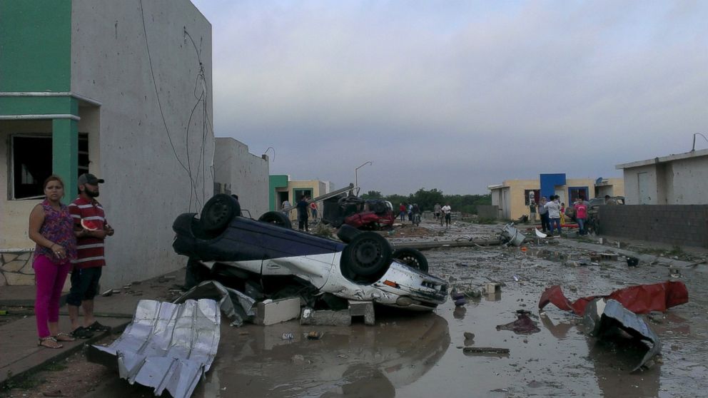 PHOTO: Residents stand next to a damaged car after a tornado hit the town of Ciudad Acuna, state of Coahuila, May 25, 2015. 