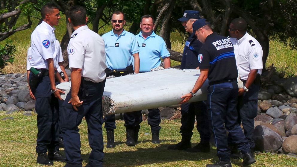 French gendarmes and police carry a large piece of plane debris which was found on the beach in Saint-Andre, on the French Indian Ocean island of La Reunion, July 29, 2015.