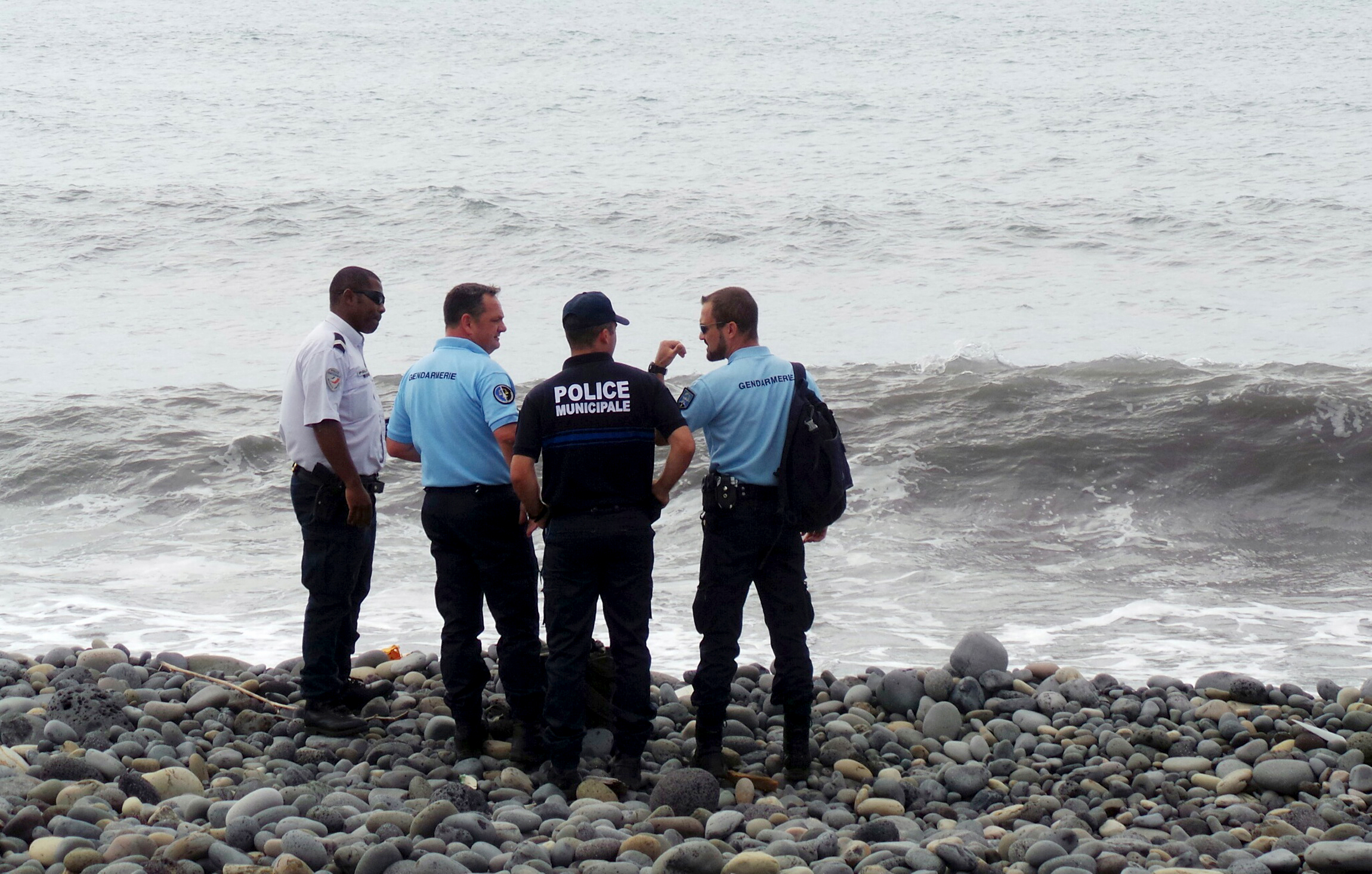 PHOTO: French gendarmes and police stand on the beach where a large piece of plane debris was found in Saint-Andre, on the French Indian Ocean island of La Reunion, July 29, 2015.