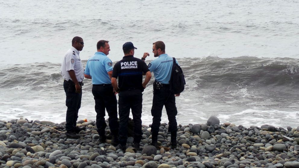PHOTO: French gendarmes and police stand on the beach where a large piece of plane debris was found in Saint-Andre, on the French Indian Ocean island of La Reunion, July 29, 2015.