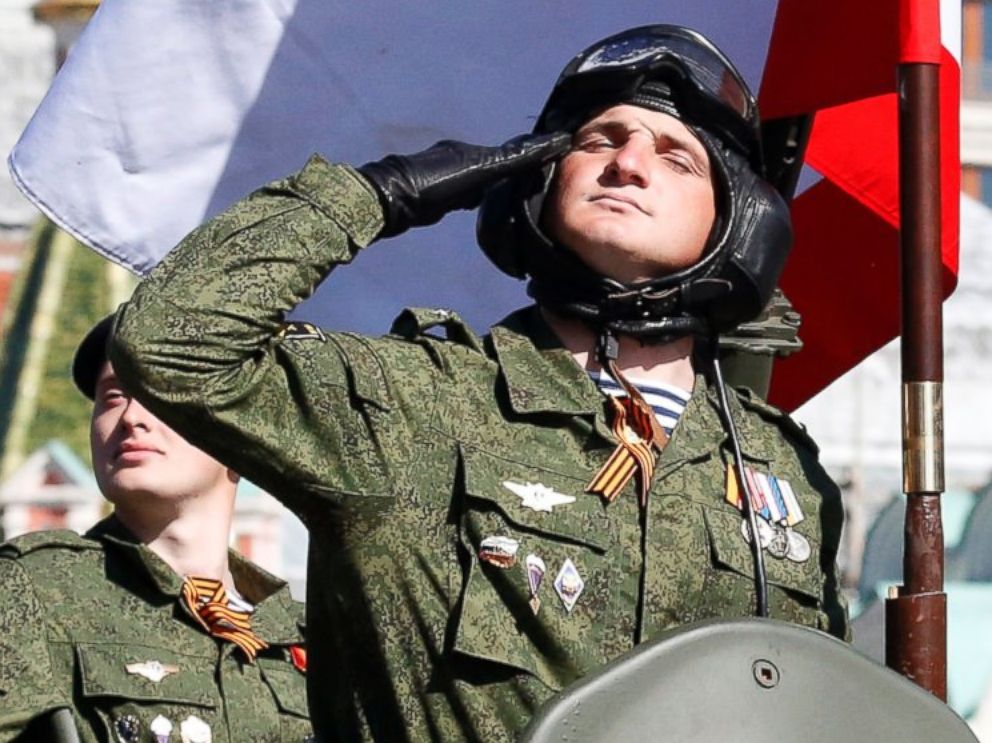 PHOTO: A Russian serviceman aboard an armored personnel carrier salutes next to the blue-white-red tricolor flag of Crimea, during the Victory Day parade at Red Square in Moscow, Russia on May 9, 2014. 
