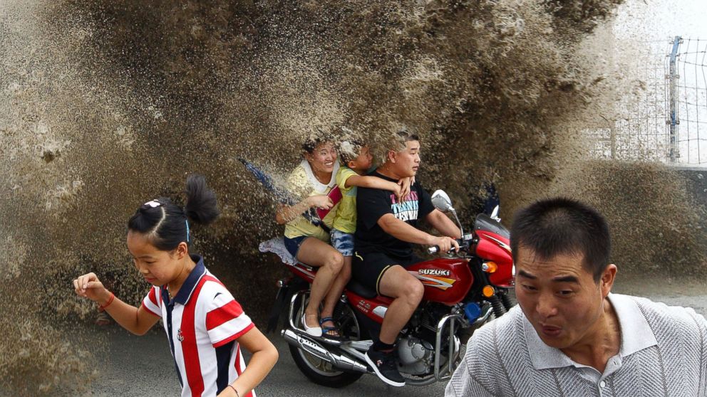 Visitors run away as waves caused by a tidal bore surge past a barrier on the banks of Qiantang River, in Hangzhou, China, Aug. 13, 2014.