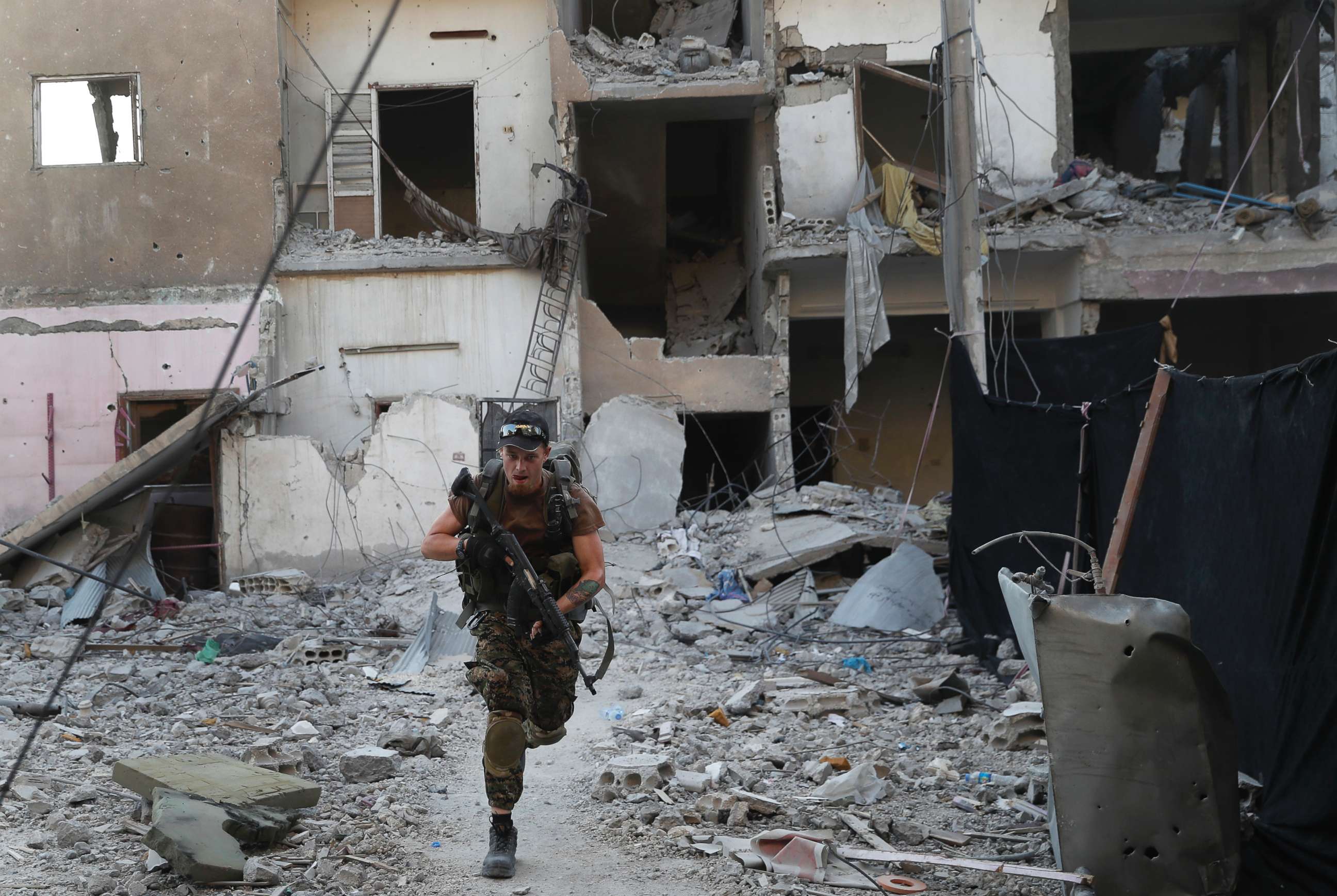 PHOTO: A U.S.-backed Syrian Democratic Forces fighter, runs in front of a damaged building as he crosses a street on the front line, in Raqqa city, Syria, July 27, 2017.