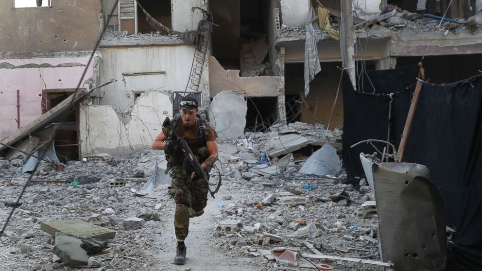 PHOTO: A U.S.-backed Syrian Democratic Forces fighter, runs in front of a damaged building as he crosses a street on the front line, in Raqqa city, Syria, July 27, 2017.