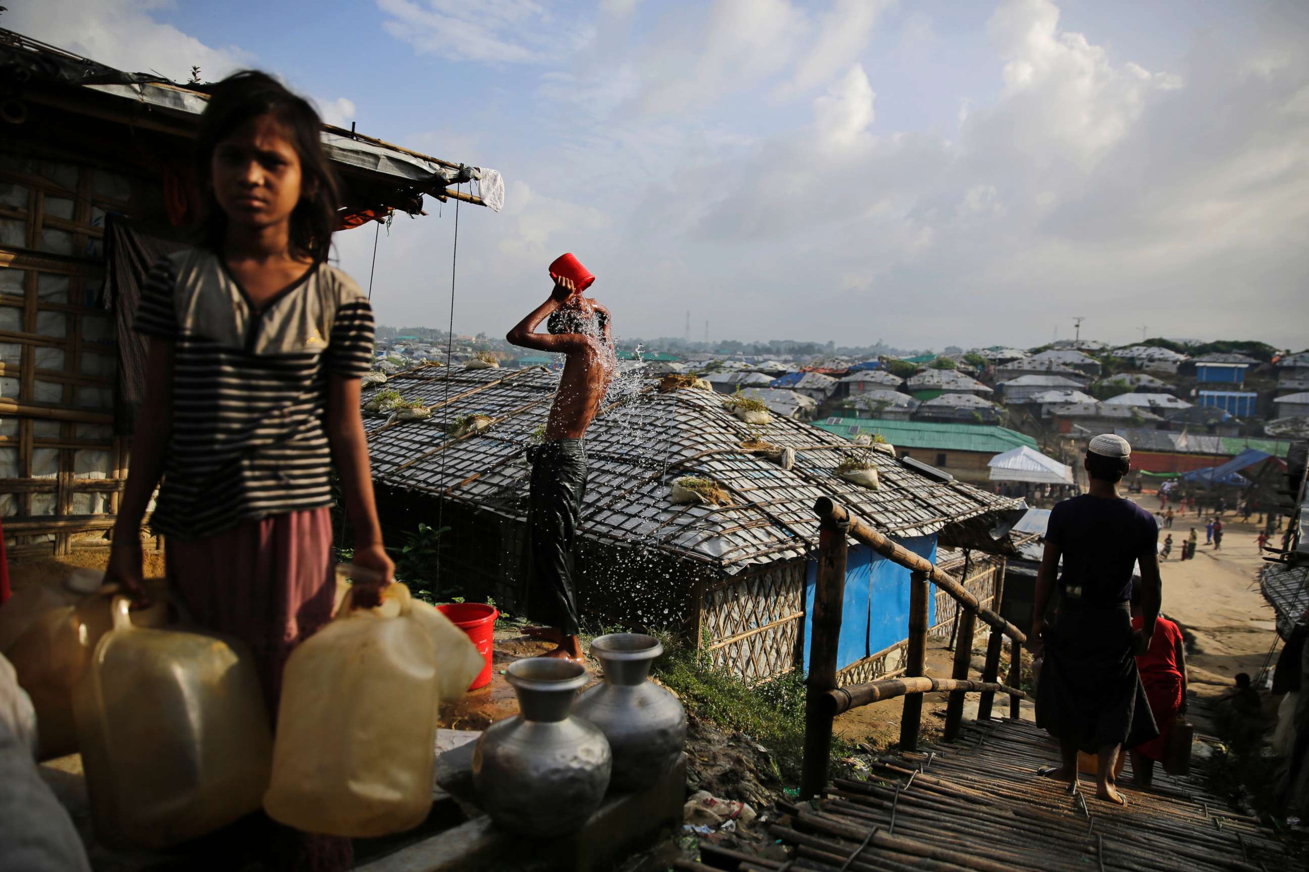 PHOTO: A Rohingya refugee bathes, as a girl waits to fill water from a hand pump at Kutupalong refugee camp, a ramshackle sprawl of camps built amid low rolling hills and endless monsoon-season mud, in Bangladesh, Aug. 22, 2018.