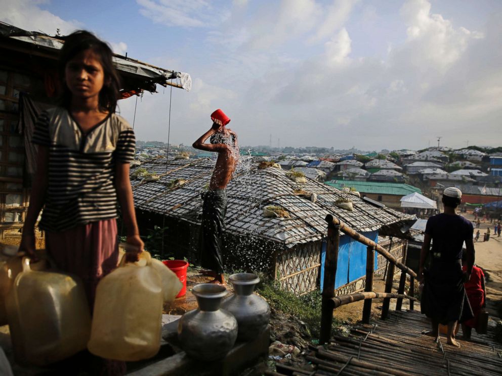 PHOTO: A Rohingya refugee bathes, as a girl waits to fill water from a hand pump at Kutupalong refugee camp, a ramshackle sprawl of camps built amid low rolling hills and endless monsoon-season mud, in Bangladesh, Aug. 22, 2018.