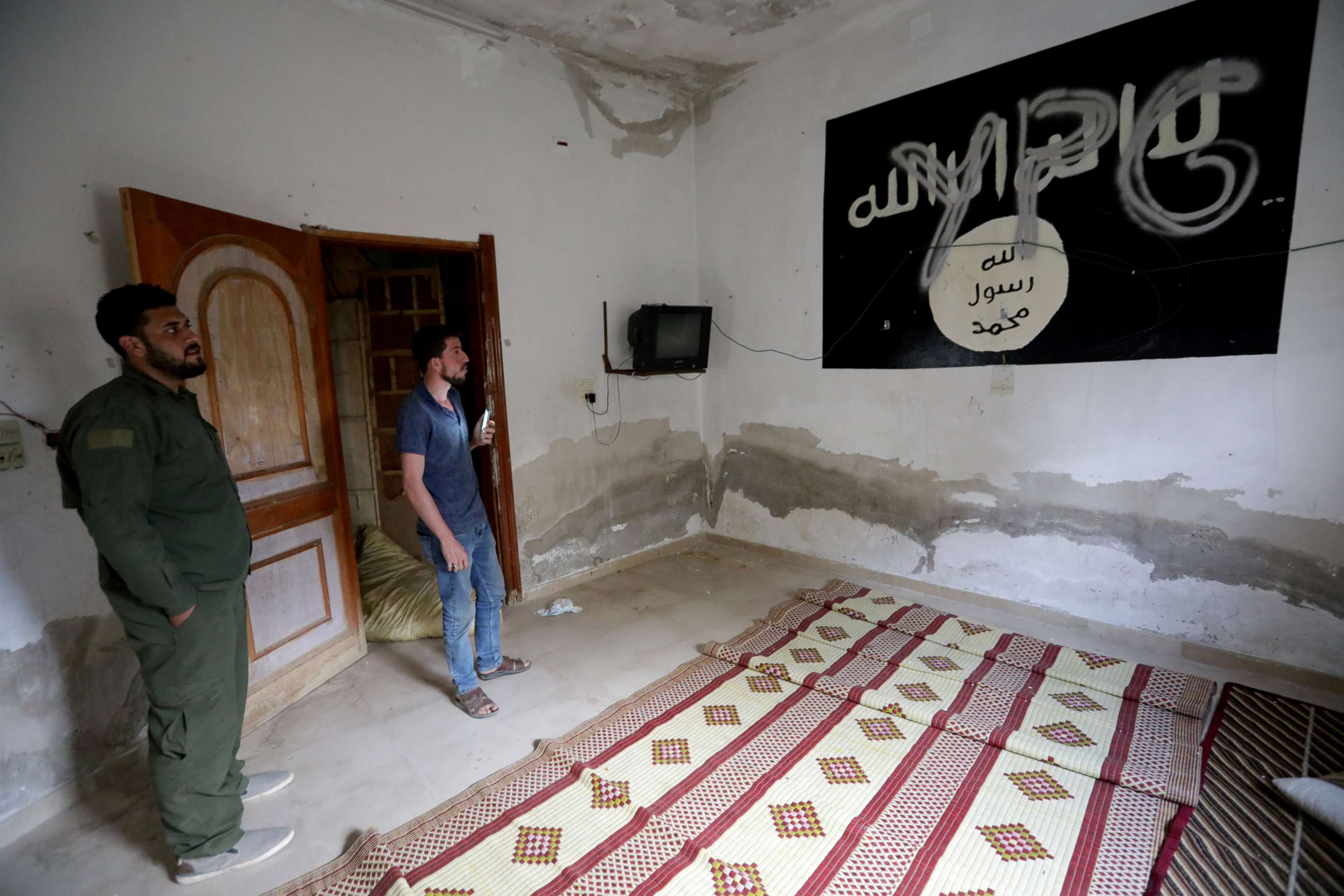 FILE PHOTO: YPG (Kurdish People's Protection Units) is written over a wall painting of ISIS flag inside a house, in the border town of Tal Abyad, Syria, October 16, 2019.