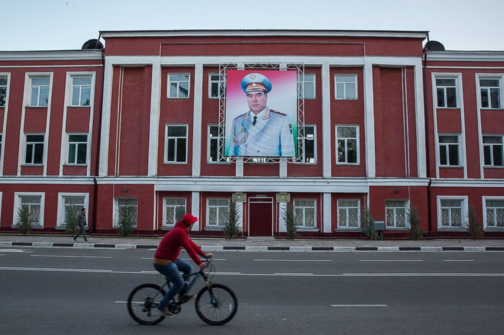 PHOTO: A cyclist rides past a banner featuring an image of Tajikistan President Emomali Rahmon displayed on a building in Dushanbe, Tajikistan, on April 22, 2018. 