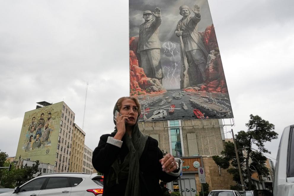 PHOTO: A woman talks on her cellphone as she walks past a billboard on a building at a square in downtown Tehran, Iran, on April 20, 2026.