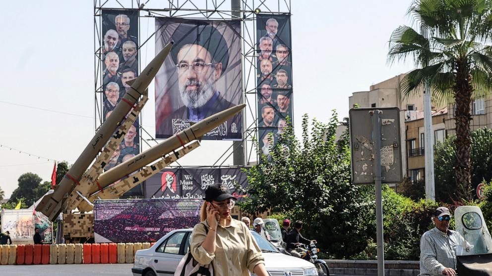 PHOTO: An Iranian woman walks past Iranian missiles on display beside a large portrait of Iran's Supreme Leader Mojtaba Khamenei at Baharestan Square in Tehran on Sept. 28, 2026.