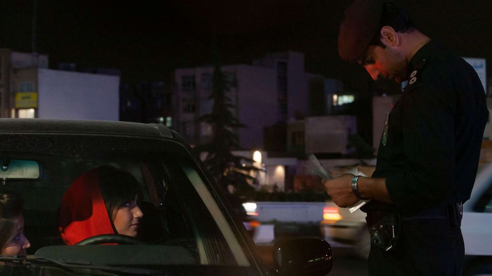 PHOTO: An Iranian woman looks at a morality policeman who checks her documents in Tehran, April 24, 2007.