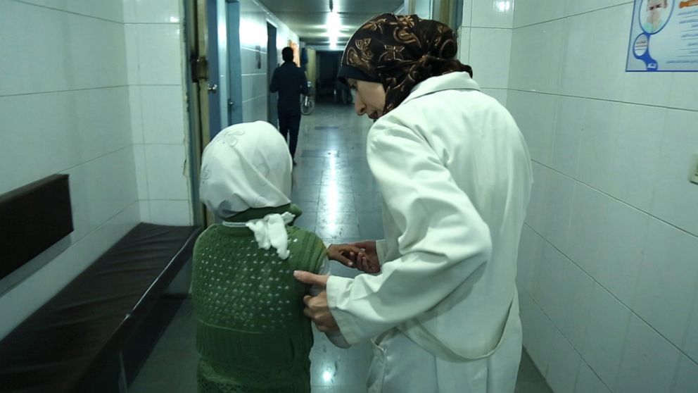 PHOTO: Dr. Amani helps a young girl into the hospital in Al Ghouta, Syria.