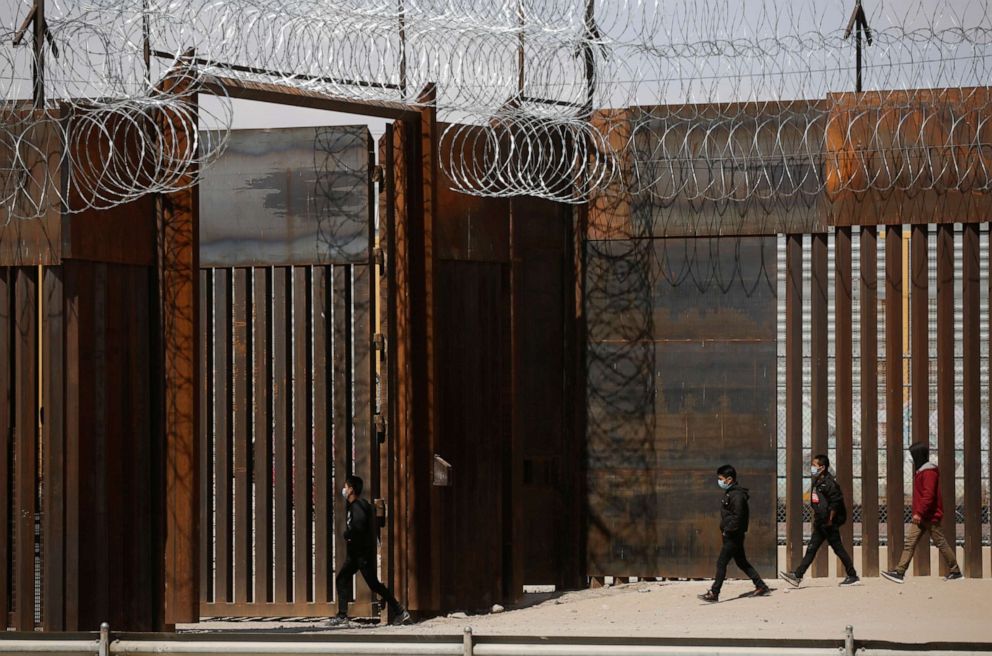 PHOTO: Migrants walk to a gate in the border wall after crossing the Rio Bravo river to turn themselves in to U.S. Border Patrol agents to request for asylum in El Paso, Texas, U.S., as seen from Ciudad Juarez, Mexico, March 14, 2021. 