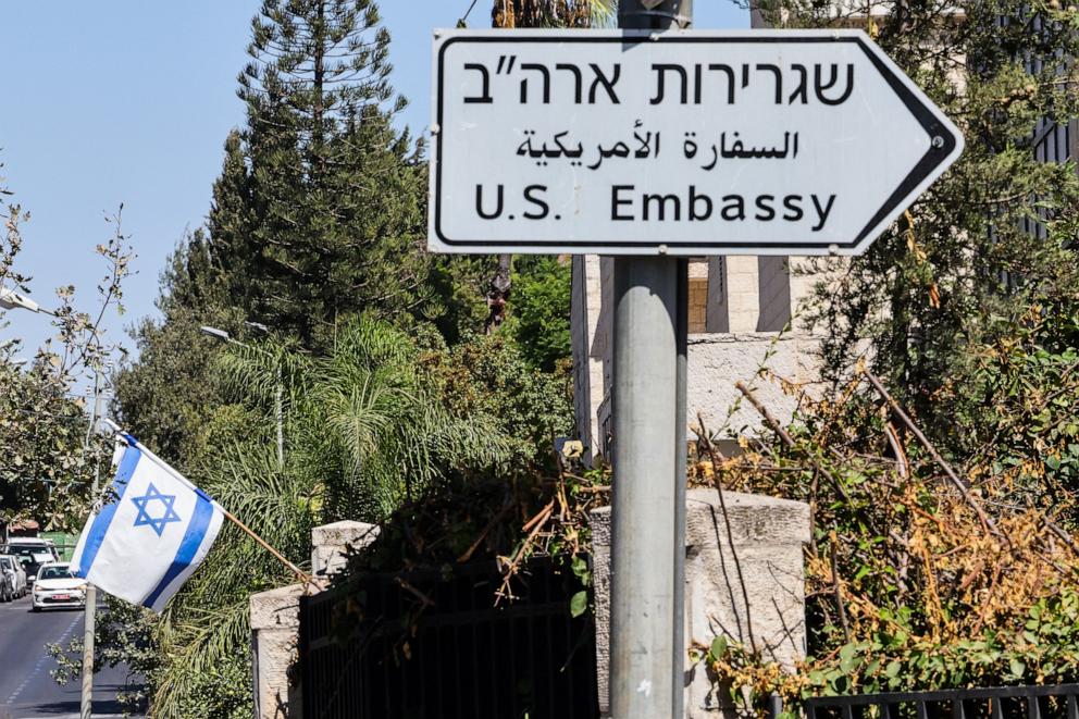 PHOTO: This file photo shows an Israeli flag displayed in front of a building near a road sign for the U.S. Embassy in Jerusalem on September 27, 2023.