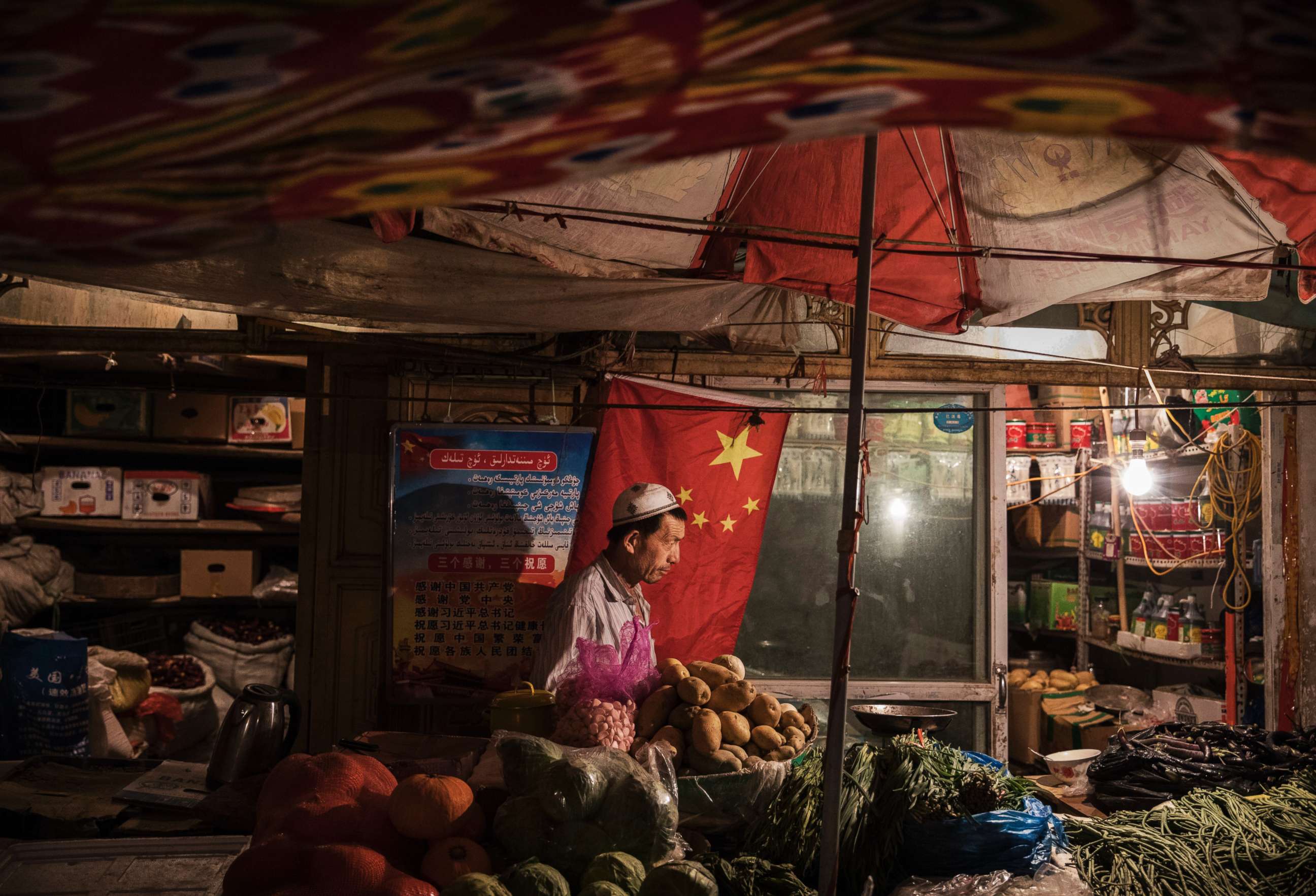 PHOTO: An ethnic Uyghur shopkeeper works next to a Chinese flag at his shop, June 29, 2017, in the old town of Kashgar, in the far western Xinjiang province, China. 