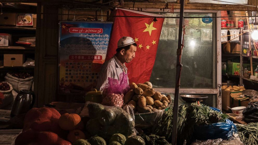 PHOTO: An ethnic Uyghur shopkeeper works next to a Chinese flag at his shop, June 29, 2017, in the old town of Kashgar, in the far western Xinjiang province, China. 