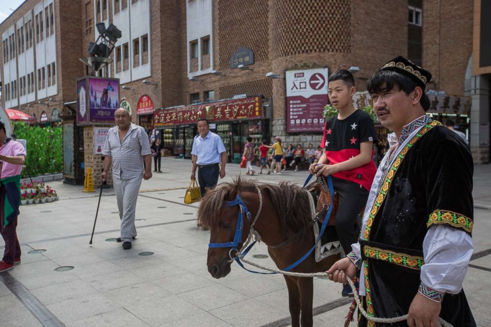 PHOTO: A Han boy rides a donkey own by a Uyghur at the Xinjiang International Grand Bazaar in Urumqi, capital of northwest China's Xinjiang Uyghur Autonomous Region in China, July 2, 2017.