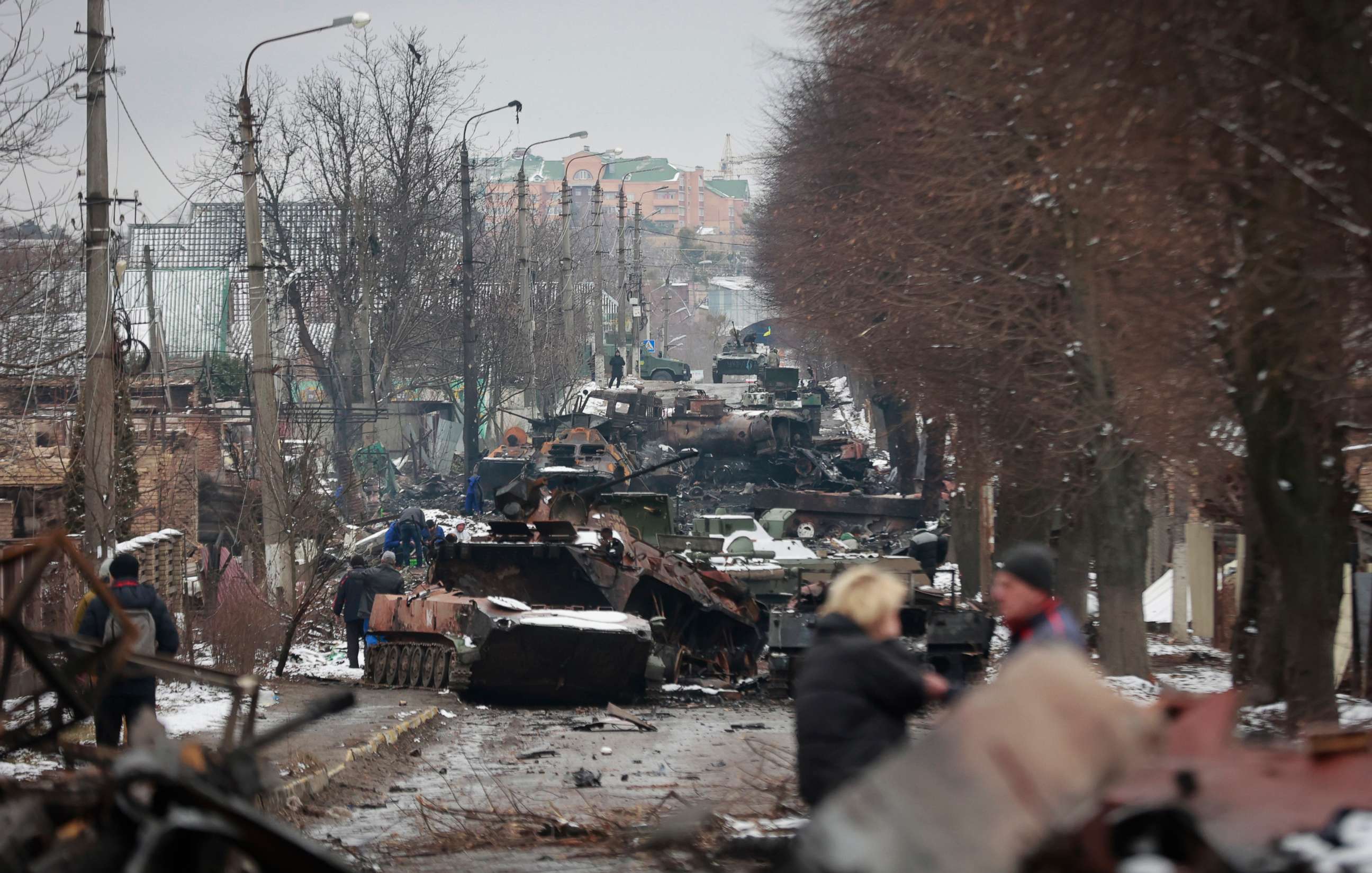 PHOTO: People look at the gutted remains of Russian military vehicles on a road in the town of Bucha, close to the capital Kyiv, Ukraine, March 1, 2022. 