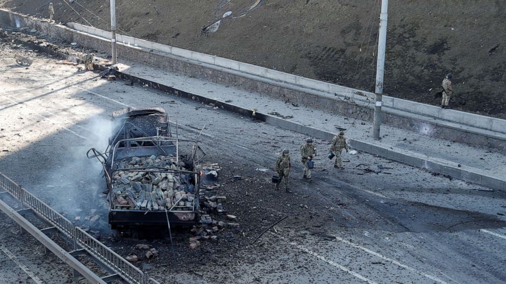 PHOTO: Ukrainian servicemen walk by a damaged vehicle, at the site of a fighting with Russian troops, after Russia launched a massive military operation against Ukraine, in Kyiv, Ukraine, Feb. 26, 2022.