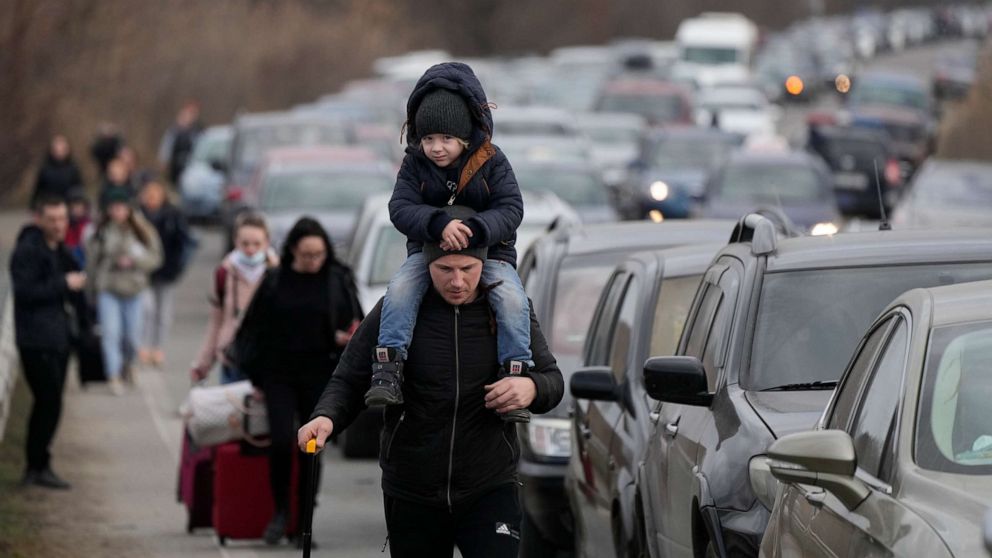 PHOTO: Ukrainian refugees walk along vehicles lining-up to cross the border from Ukraine into Moldova, at Mayaky-Udobne crossing border point near Mayaky-Udobne, Ukraine, Feb. 26, 2022.