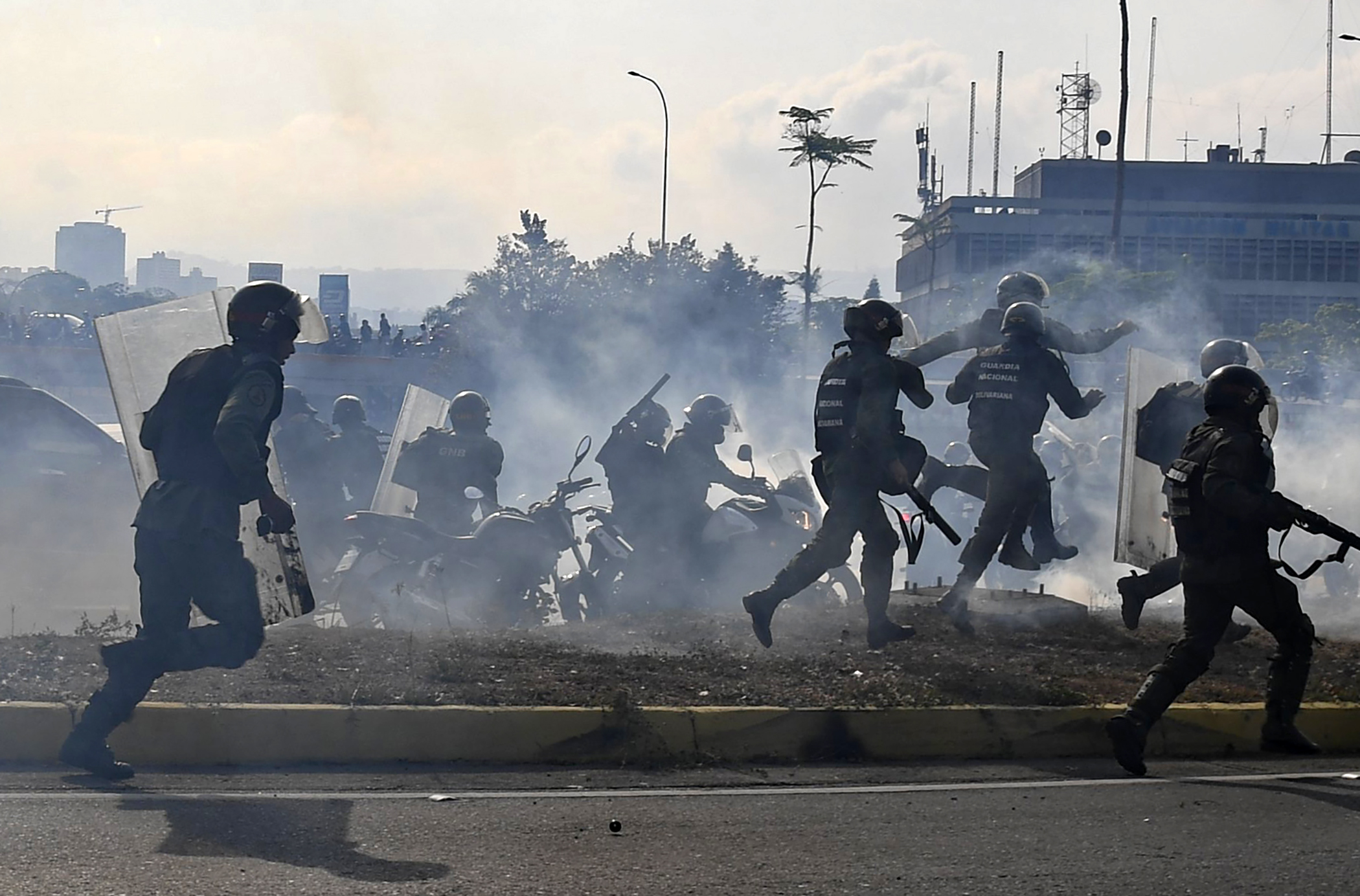 PHOTO: Members of the Bolivarian National Guard loyal to Venezuelan President Nicolas Maduro run under a cloud of tear gas after being repelled with rifle fire by guards supporting Venezuelan opposition leader Juan Guaido in Caracas, April 30, 2019. 