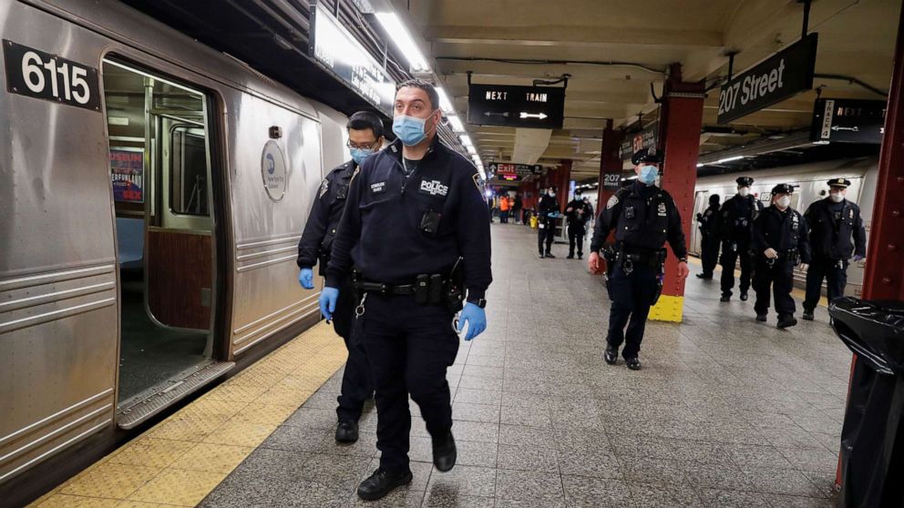 PHOTO: NYPD and MTA officers search cars for sleeping passengers and direct them to the exits at the 207th Street A-train station, April 30, 2020, in the Manhattan borough of New York.