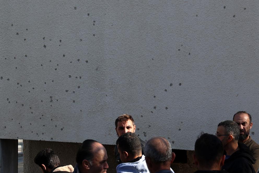 PHOTO: Palestinian men stand in front of a bullet riddled wall after a raid by Israeli forces, in the village of Tamun near Nablus in the northern occupied West Bank, on Jan. 8, 2025.