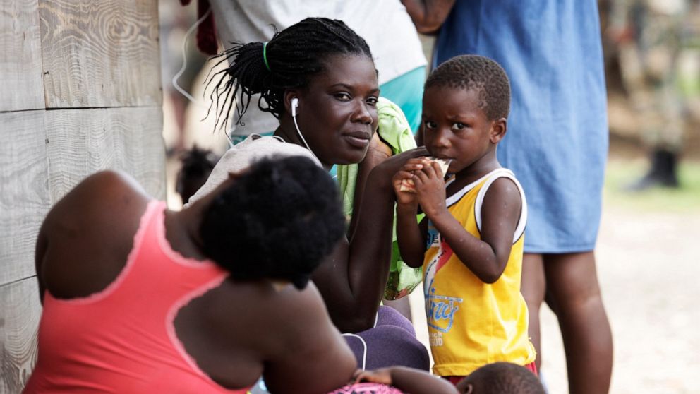Women and children sit idle at a migrant camp amid the new coronavirus pandemic in Lajas Blancas, Darien province, Panama, Saturday, Aug. 29, 2020. In Lajas Blancas, the migrants did not wear masks or practice social distancing, but Panama's Public S