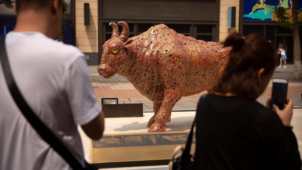 Visitors take photos of a statue of a bull along a shopping street in Beijing, Friday, June 7, 2019. Asian shares were mostly higher Friday on investor optimism about a possible trade deal between the U.S. and Mexico before tariffs take effect. (AP P