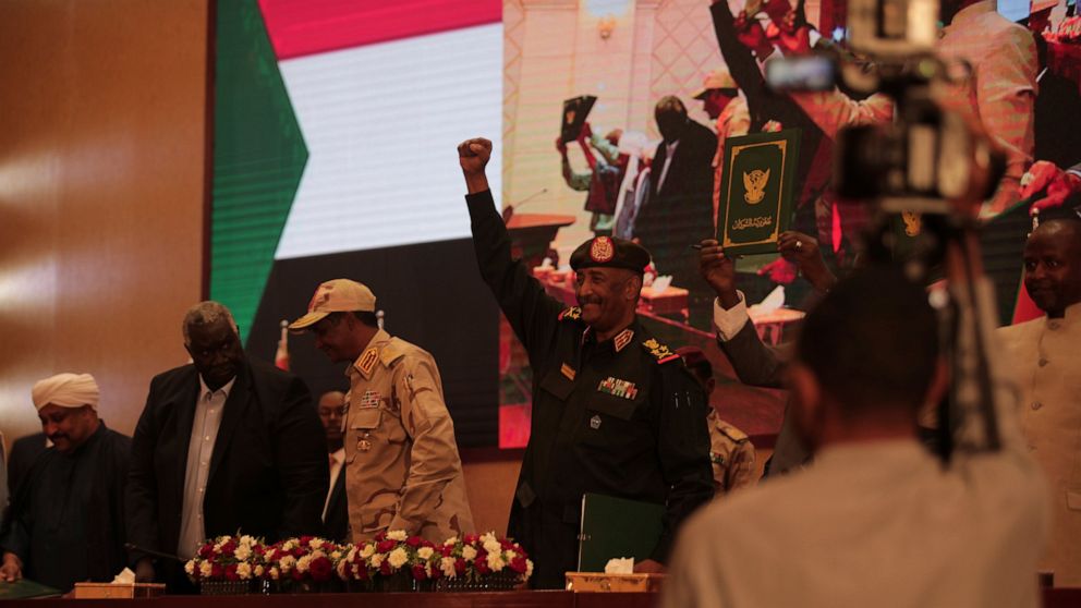 Sudan's Army chief Gen. Abdel-Fattah Burhan, center, holds up his fist as others hold a document following the signature of an initial deal aimed at ending a deep crisis caused by last year's military coup, in Khartoum, Sudan, Monday, Dec. 5, 2022. S