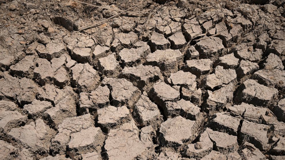 FILE - Cracked dry mud is seen in a community reservoir that ran nearly empty after its retaining wall started to leak and hot weather and drought conditions accelerated the loss of water Longquan village in southwestern China's Chongqing Municipalit