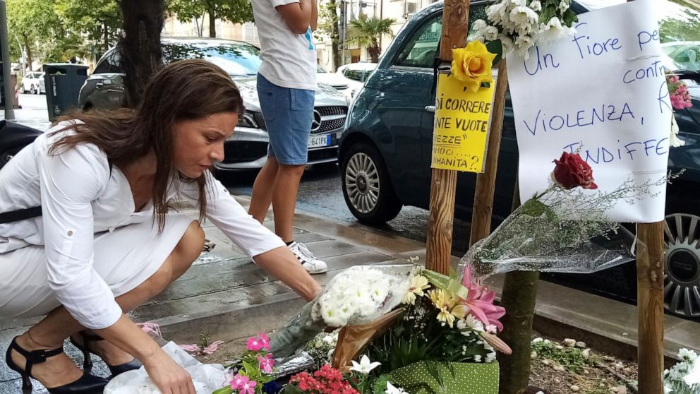 FILE - A woman places a bouquet of flowers where Nigerian street vendor Alika Ogorchukwu was murdered, in Civitanova Marche, Italy, Saturday, July 30, 2022. A judge in Italy on Monday ordered an Italian man to remain jailed as an investigation contin