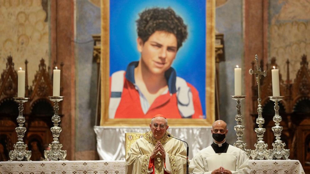 An image of 15-year-old Carlo Acutis, an Italian boy who died in 2006 of leukemia, is seen during his beatification ceremony celebrated by Cardinal Agostino Vallini, center, in the St. Francis Basilica, in Assisi, Italy, Saturday, Oct. 10, 2020. (AP 