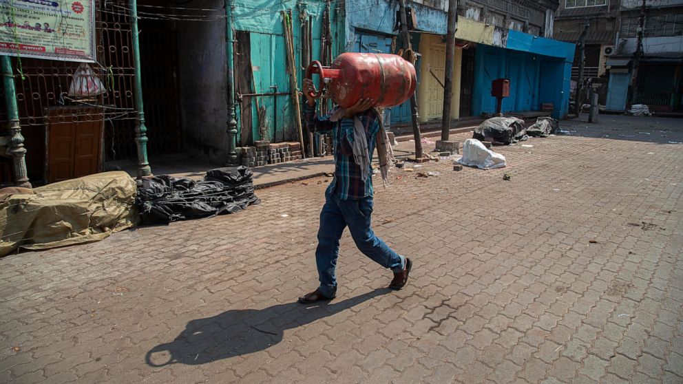 An Indian man walks carrying a cooking gas cylinder in Gauhati, India, Wednesday, March 25, 2020. The world's largest democracy went under the world's biggest lockdown Wednesday, with India's 1.3 billion people ordered to stay home in a bid to stop t