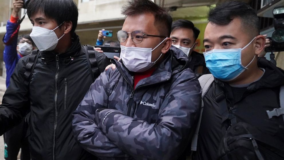 FILE - Senior editor of "Stand News" Ronson Chan, center, is arrested by police officers in Hong Kong on Dec. 29, 2021. Chan was granted bail Thursday, Sept. 22, 2022 and allowed to leave the city for an overseas fellowship two weeks after he was arr