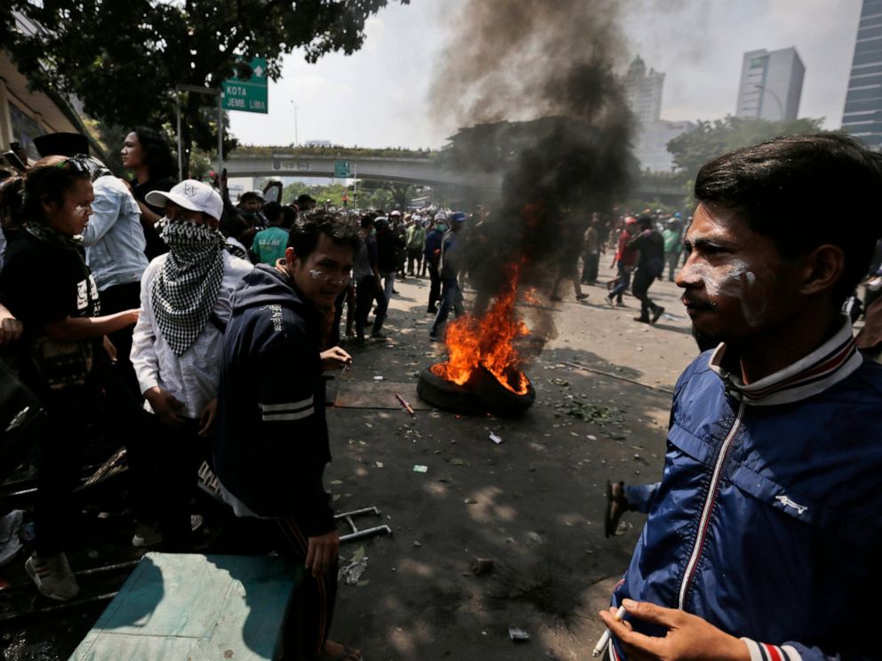 Protesters rest near burning tires during a clash with the police in Jakarta, Indonesia, Wednesday, May 22, 2019. Supporters of an unsuccessful presidential candidate clashed with security forces in the Indonesian capital on Wednesday, burning vehicl