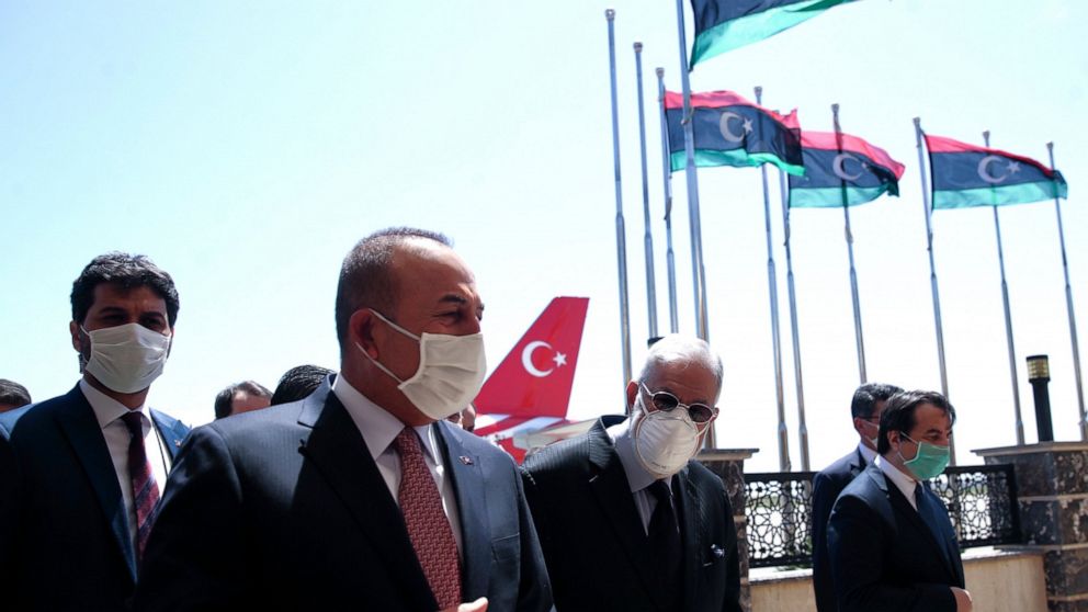 FILE - In this June 17, 2020, file photo, Turkey's Foreign Minister Mevlut Cavusoglu, left, and Muhammed Tahir Siyala, Foreign Minister of Libya's internationally-recognized government, speak at the airport, in Tripoli, Libya. Libya’s eastern-based f