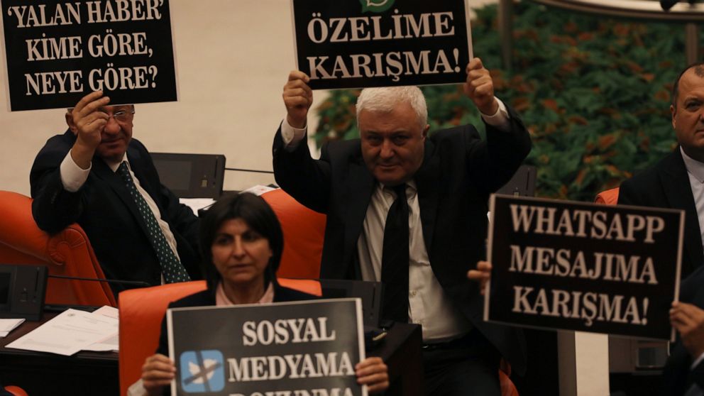 Lawmakers from the main opposition Republican People's Party hold up placards in protest at the parliament, in Ankara, Turkey, Tuesday, Oct. 11, 2022. Turkey's parliament continued to debate a highly controversial draft law Tuesday in Ankara. The gov