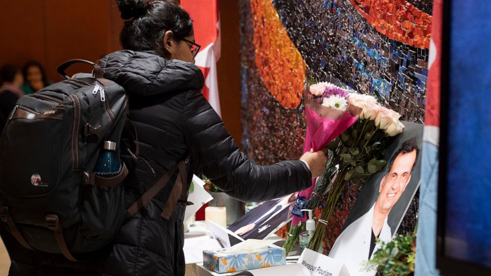 Flowers are laid beside books of condolence before ceremony at Carleton University Wednesday, Jan. 15, 2020 to honor biology PhD student Fareed Arastech and biology alumnus Mansour Pourjam, who died in the crash of Ukraine International Airlines Flig