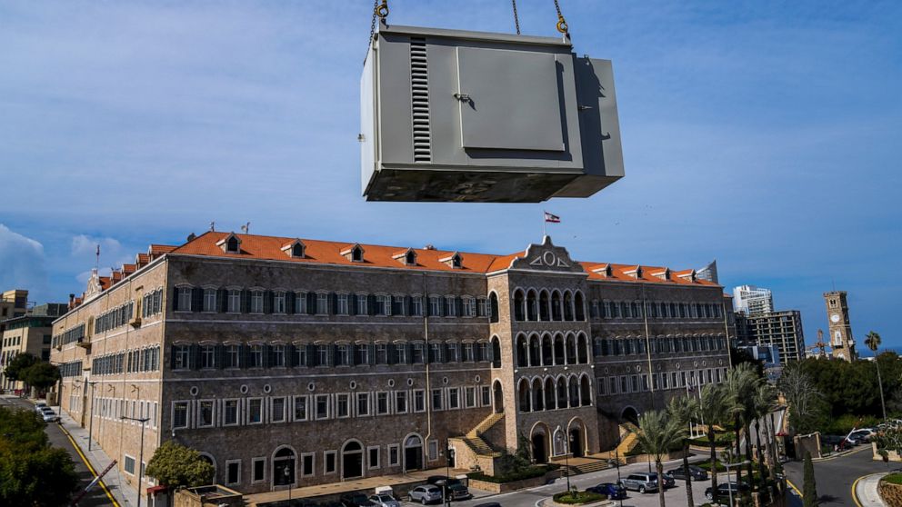 With the Lebanese Government House in the background, a new generator is hauled up to the roof of an office building, in Beirut, Lebanon, Feb. 21, 2022. They literally run the country. Private generators are ubiquitous in parts of the Middle East, sp