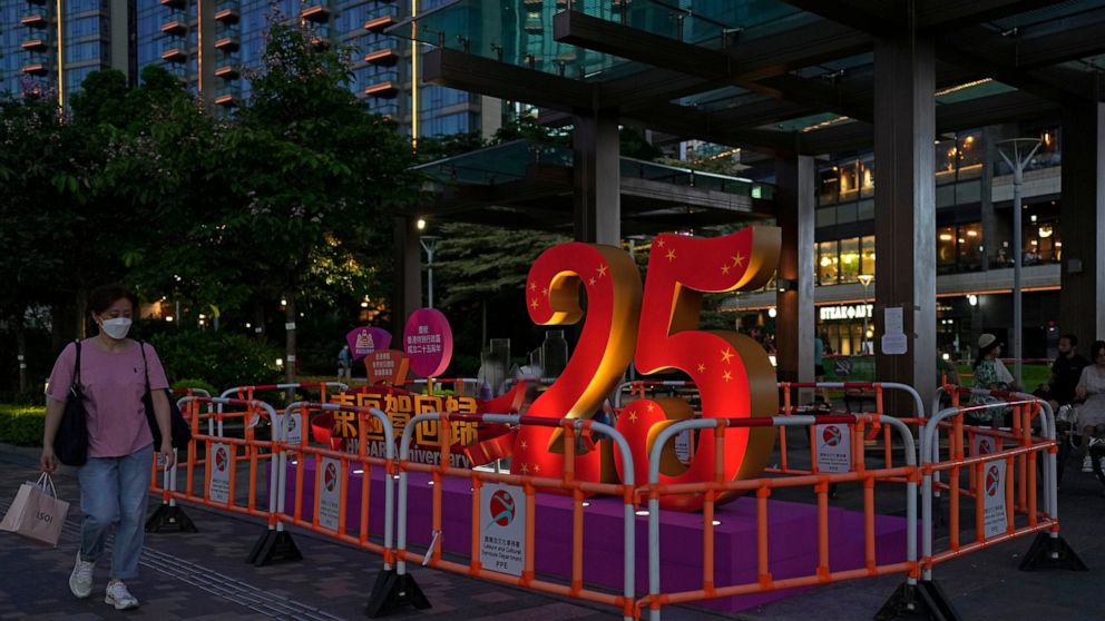 FILE - A woman walks past a sculpture to celebrate the 25th anniversary of Hong Kong handover to China, in Hong Kong, Friday, June 24, 2022. Hong Kong authorities, citing “security reasons,” have barred more than 10 journalists from covering events a