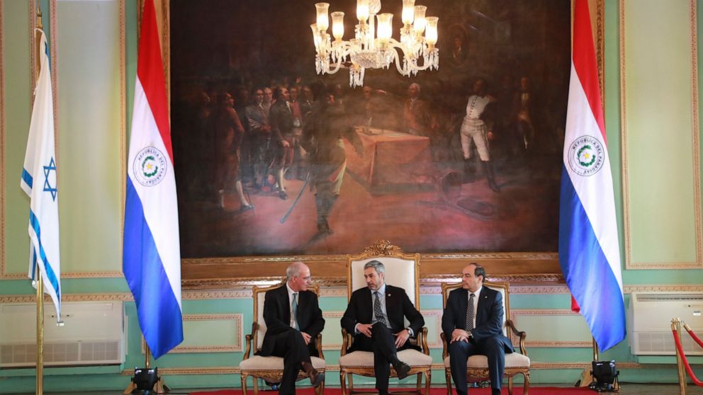In this hand out picture released by Paraguay's Government Press Office, President Mario Abdo Benitez, center, talks to Israel's new ambassador to Paraguay, Yoed Magen, left, as Foreign Minister Antonio Rivas Palacios, right, listens, during official