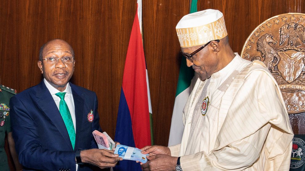 In this photo released by the Nigeria State House, Nigeria's central bank governor, Godwin Emefile, left, presents the newly designed currency notes to Nigeria's President Muhammadu Buhari, right, during a launch in Abuja, Nigeria, Tuesday, Nov. 22, 