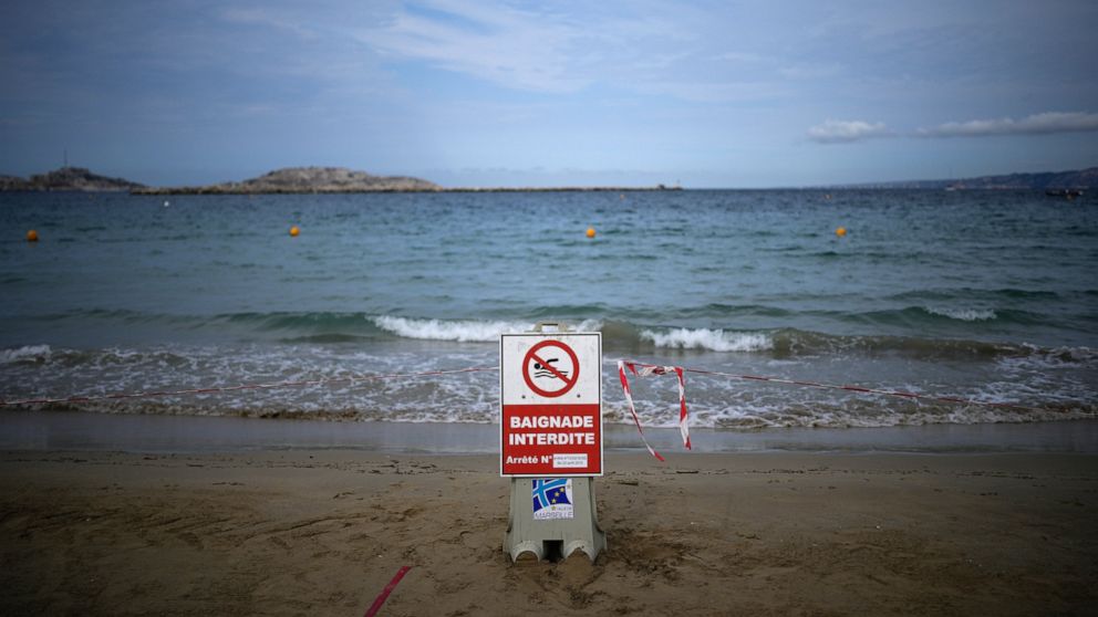 A sign reading "swimming prohibited" sits on a beach with high levels of pollution the morning after a storm passed through Marseille, southern France, Thursday, Aug 18, 2022. (AP Photo/Daniel Cole)
