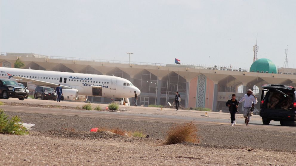 People walk away from the runway following an explosion at the airport in Aden, Yemen, shortly after a plane carrying the newly formed Cabinet landed on Wednesday, Dec. 30, 2020. No one on board the government plane was hurt but initial reports said 